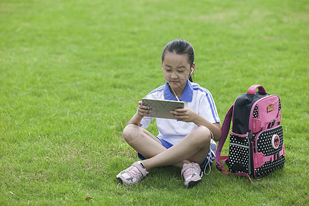 女同学在学校草坪上用ipad学习背景图片