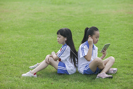 女同学在学校里草坪上用ipad 学习背景图片