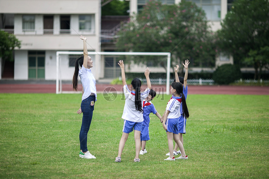 校园里女老师和同学们在草坪上一起玩耍