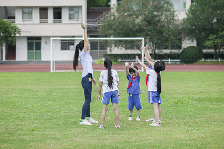 校园里女老师和同学们在草坪上一起玩耍图片