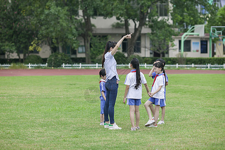 校园里女老师和同学们在草坪上一起玩耍图片