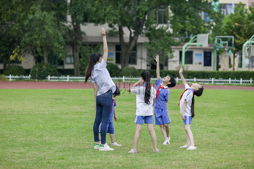 校园里女老师和同学们在草坪上一起玩耍