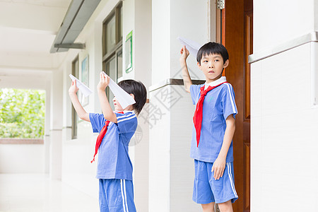 学生玩纸飞机下课在走廊上玩飞机的小学生背景
