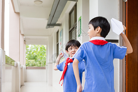 学生玩纸飞机下课在走廊上玩飞机的小学生背景