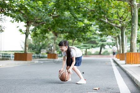 校园林荫道上打篮球的小学生女生背景图片