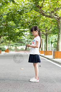 站在校园里玩手机的小学生女生图片