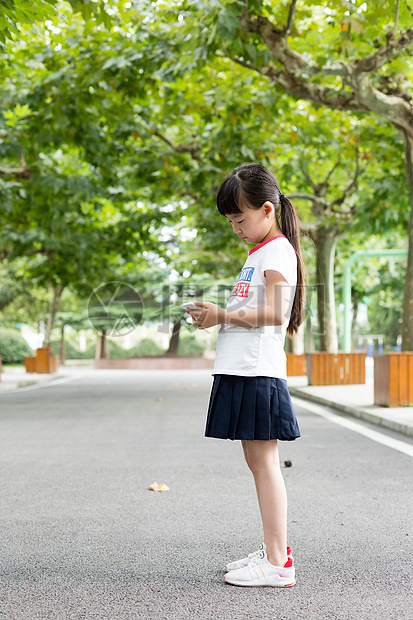 站在校园里玩手机的小学生女生图片