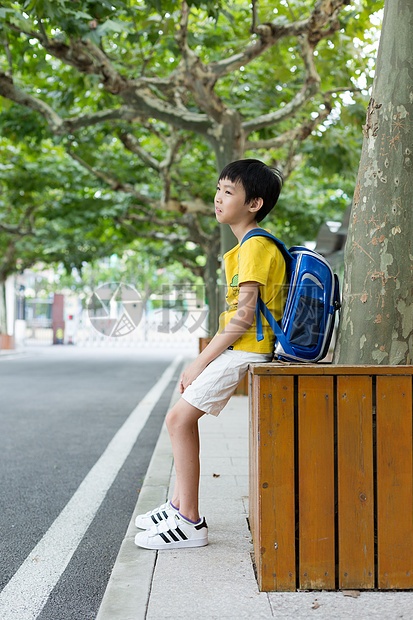 校园林荫道坐着等待家长的小学生图片