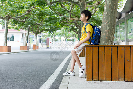 校园林荫道坐着等待家长的小学生图片