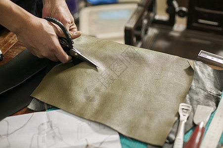 匠心制作皮匠在专注的裁剪皮革背景