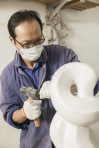 专注的石匠雕刻师傅在雕刻作品图片