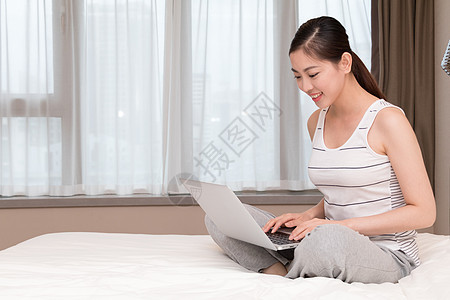年轻女性在床上玩电脑图片