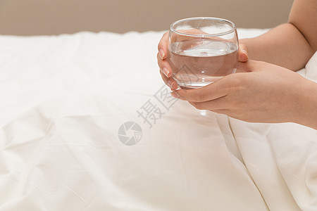 早起起床拿着水杯喝水特写图片