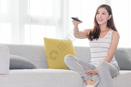 年轻女性在沙发上使用遥控器图片