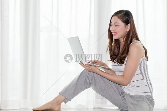 坐在窗台使用电脑休闲放松的女性图片