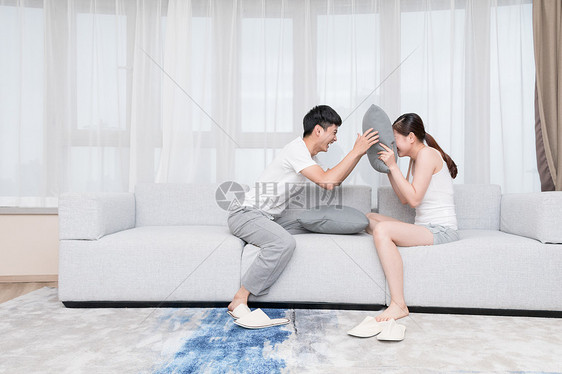 年轻情侣夫妻在客厅抢枕头图片