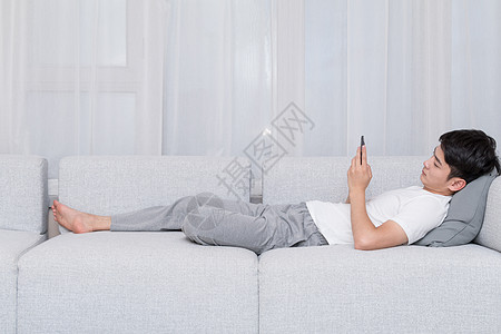 躺沙发上男生躺在沙发上玩手机购物背景