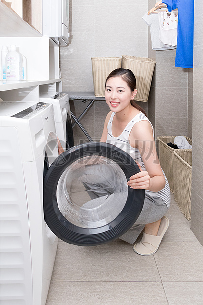 使用洗衣机洗衣服的家庭女性图片