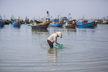 站在船上的人海边渔民在专注的劳作背景
