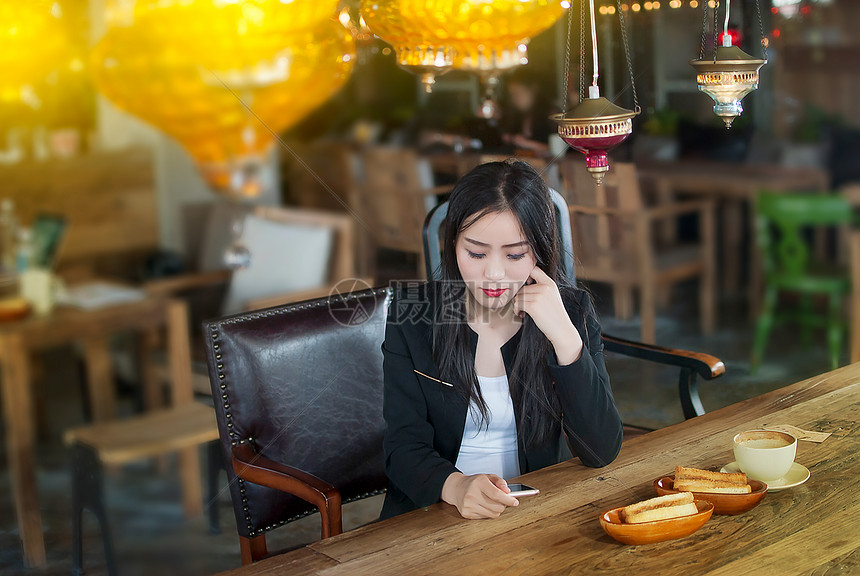 咖啡馆看手机的商务女性图片