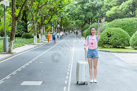 校园内女生拉旅行箱挥手背景图片