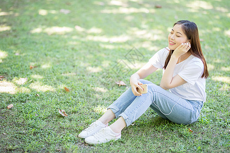 校园草坪上看手机听音乐的女生图片