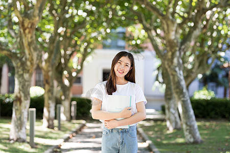 女大学生抱书图走在校园林荫道下的甜美女生背景
