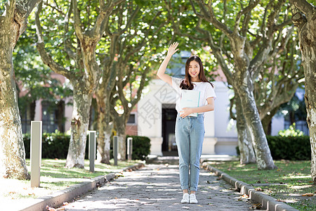 长发美女校园里拿着书微笑打招呼的女生背景