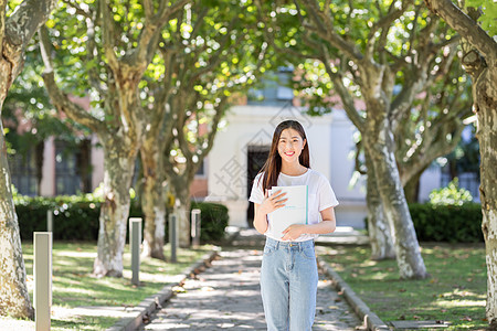 女大学生抱书图走在校园林荫道下的甜美女生背景