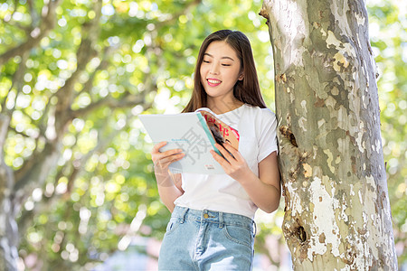 长发美女校园里靠在大树边看书的女生背景