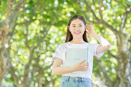 校园林荫道上微笑看书的学生图片