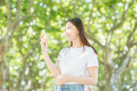 树下用手机听音乐的甜美女生图片