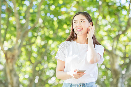 树下用手机听音乐的甜美女生图片