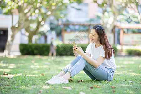 坐在校园草坪上玩手机的女生图片