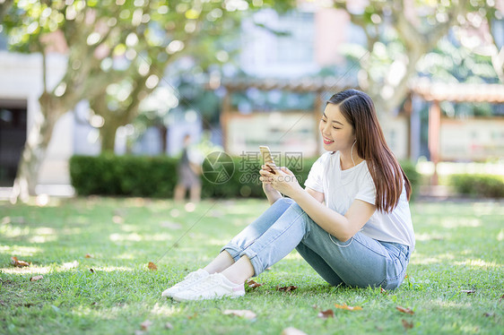 坐在校园草坪上玩手机的女生图片