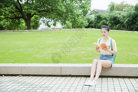 校园草地前女生在看书图片