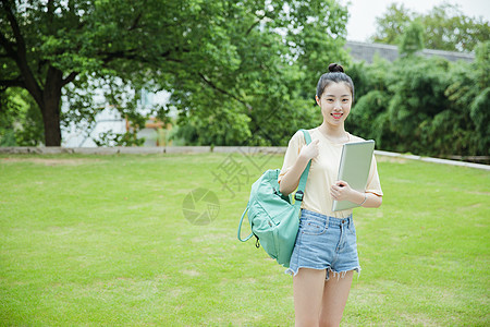 校园草地前女生抱着电脑图片