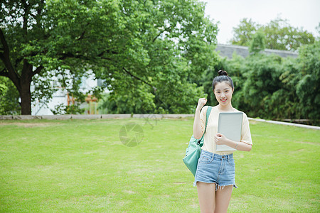 校园草地前女生抱着电脑高清图片