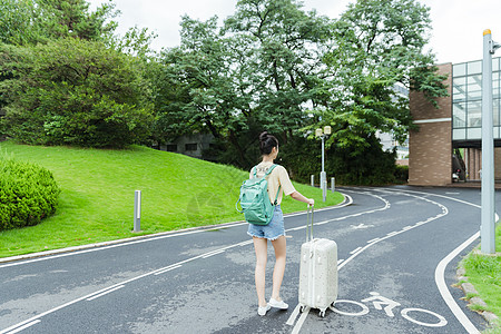 旅行箱背影校园里拉着旅行箱的女生背影背景