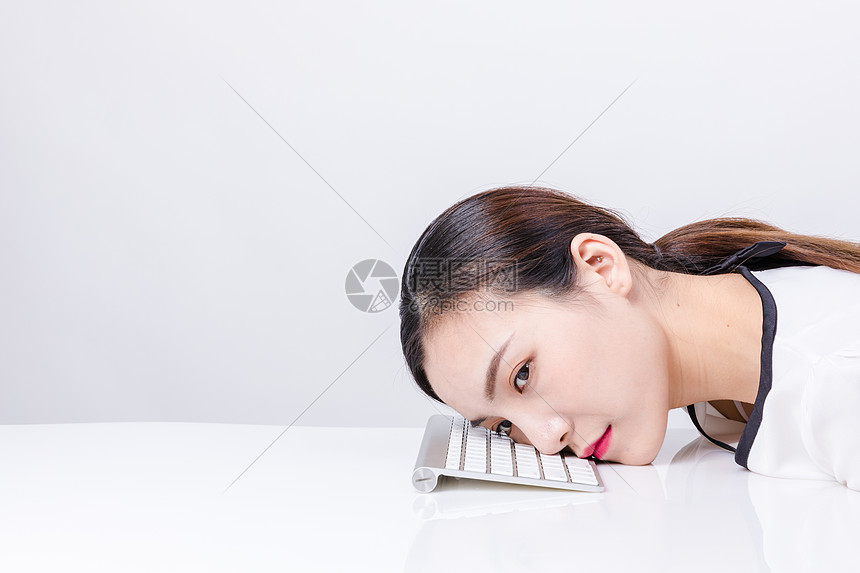 职业女性靠在键盘上棚拍图片