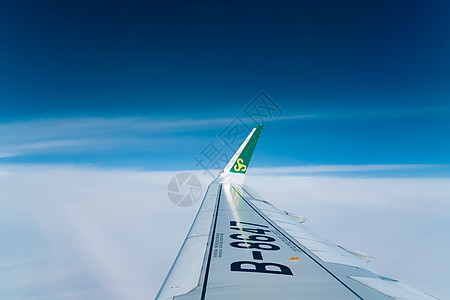 旅途中舷窗外蓝天中的机翼背景图片