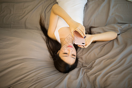 躺在床上玩手机的美女背景图片