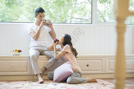 年轻情侣在客厅拍照背景图片