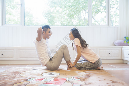 年轻夫妇在客厅做仰卧起坐背景