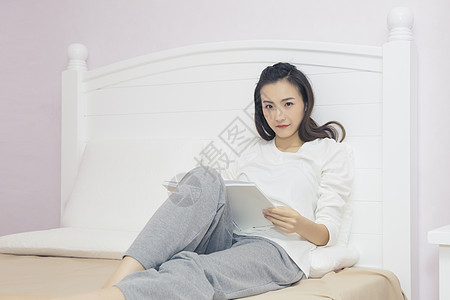 年轻女性在卧室看书图片