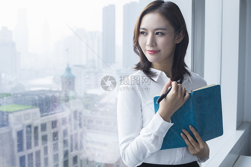 女白领在落地窗前站立：商务办公的成功人士图片