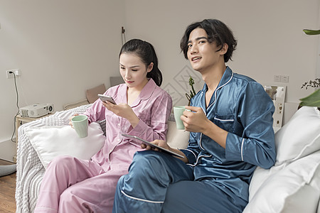 情侣在客厅休息玩手机平板电脑高清图片