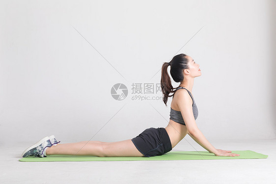 瑜伽垫上做运动动作的年轻女性图片