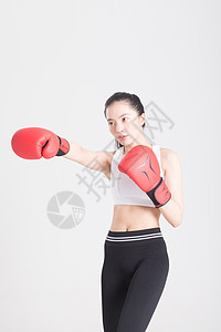 戴着拳击手套打拳出拳的年轻运动女性背景图片