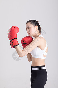 戴着拳击手套打拳出拳的年轻运动女性背景图片